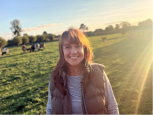 Fi Holder on the family farm, with cattle in the field behind her